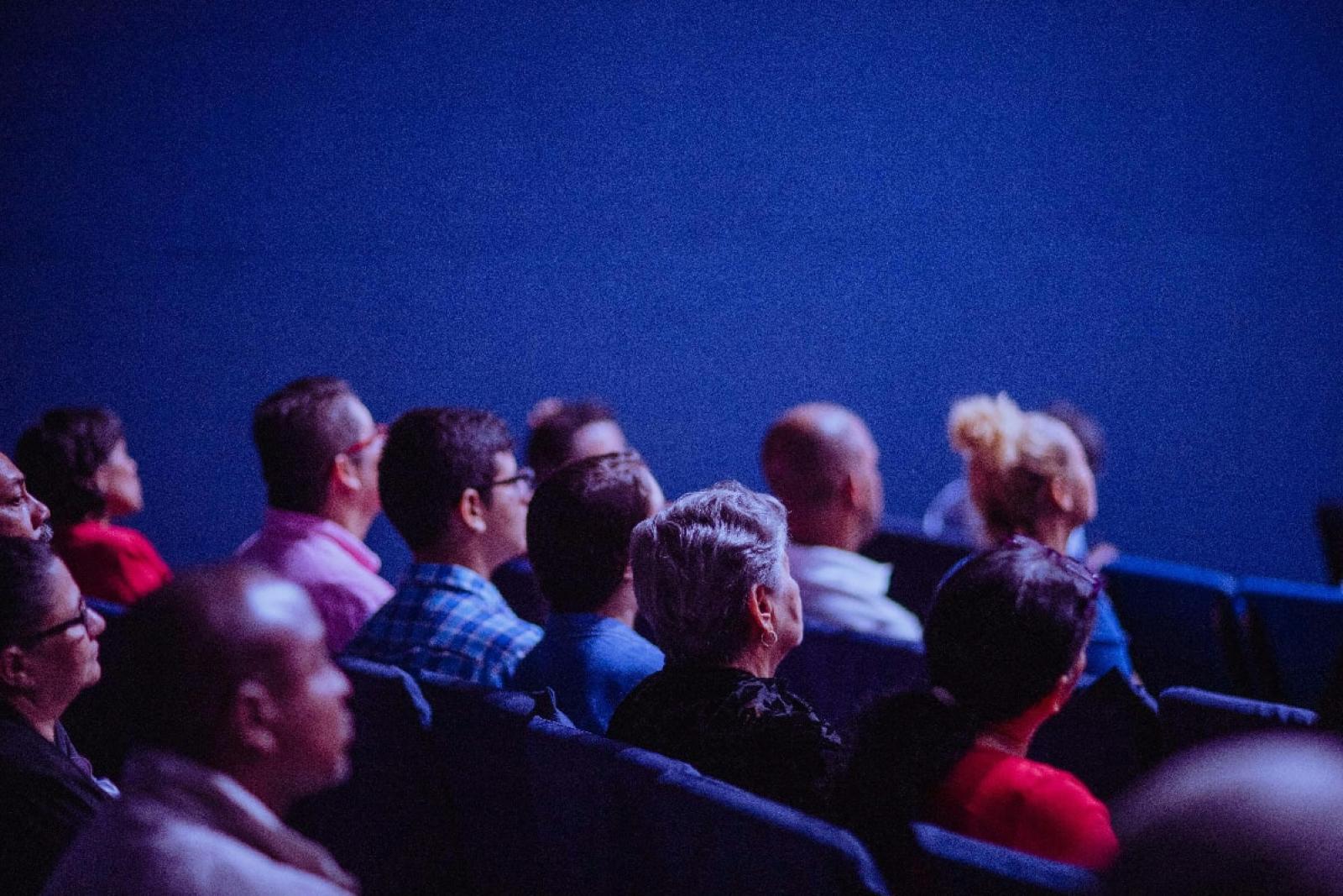 Group of people in rows of seats listening to presentation